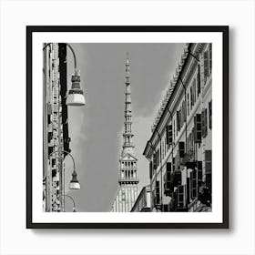 Urban View of a Historic Spire. The image depicts a black-and-white urban scene featuring a tall, ornate spire rising prominently in the center. The spire is framed by two rows of buildings with numerous windows and balconies, creating a symmetrical perspective. Street lamps hang from curved poles on the left side of the image, adding to the urban atmosphere. The architectural details and the height of the spire make it a focal point, suggesting it is a significant landmark. Art Print