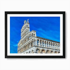 Lucca Majestic Facade: The Elegance of Romanesque Architecture. This image highlights the intricate facade of a Romanesque-style church under a vibrant blue sky. The series of arches, columns, and detailed sculptures create a harmonious display of historical craftsmanship, crowned by statues of angels that enhance the monument's grandeur. Art Print