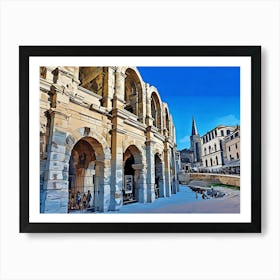 Roman Amphitheater in Arles. The image showcases the ancient Roman amphitheater in Arles, France. The imposing stone structure features a series of arches and columns, with a weathered facade and a hint of the interior visible. The amphitheater stands against a backdrop of a clear blue sky, with a church spire peeking out in the distance. Art Print