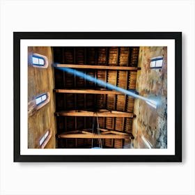 Heavenly Light. A captivating view of a wooden church ceiling in Pisa, with natural light streaming through small arched windows. The interplay of light and shadows highlights the intricate beams and aged walls, creating a serene and spiritual atmosphere. Art Print