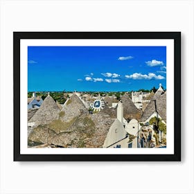 Trulli Houses in Italy. The image showcases a picturesque view of a traditional Italian village, featuring a cluster of Trulli houses with their distinctive conical roofs. The houses are constructed from white stone and have a rustic charm, with some roofs adorned with intricate patterns. The scene is bathed in warm sunlight, with a clear blue sky and fluffy white clouds overhead. Art Print