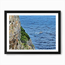 Boat on the Sea near Capo Caccia Sardinia. This image shows a view from the top of a steep, winding staircase descending between two rugged limestone cliffs toward the blue Mediterranean Sea. A small boat cruises along the calm waters in the distance, adding a sense of scale to the vastness of the sea. This scene captures the dramatic coastal landscape of Capo Caccia in Sardinia, Italy. 1 Art Print