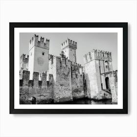 Medieval Castle by the Water Castello Scaligero Sirmione Lake Garda. A black and white illustration depicts a majestic medieval castle with towering stone walls and crenellated towers. The castle stands majestically by a body of water, possibly a moat or a lake, with a small bridge leading to the entrance. The intricate details of the stonework and the imposing presence of the castle create a sense of history and grandeur. Art Print