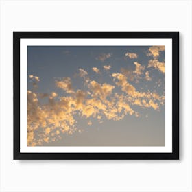 Golden clouds in the pale blue sky at sunset Art Print