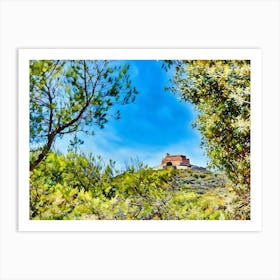 Path to the Red Fortress. A winding path leads through a rugged, green-dotted landscape to a striking red fortress perched atop a hill, blending history with natural beauty under a vivid blue sky. 1 Art Print