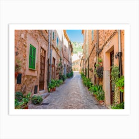 Beautiful street at the mediterranean village of Valldemossa on Majorca Spain. Wander through beautiful streets lined with historic buildings adorned with blooming flowers and lush plants. Admire the intricate architecture and facades of the old houses, and feel the romance in the air. Art Print