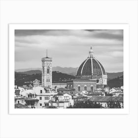 Florence Cathedral and Giotto's Campanile. This black and white photograph captures the iconic Florence Cathedral (Duomo) and Giotto's Campanile in Florence, Italy. The image showcases the architectural grandeur of the cathedral's large dome and the intricate details of the bell tower, set against a backdrop of rolling hills and a cloudy sky. The foreground includes a mix of traditional Italian buildings, adding to the historical ambiance of the scene. Art Print