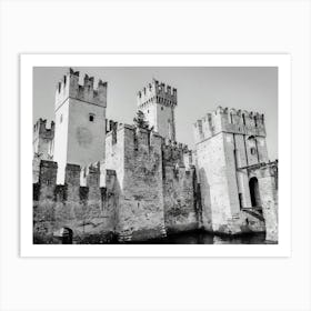 Medieval Castle by the Water Castello Scaligero Sirmione Lake Garda. A black and white illustration depicts a majestic medieval castle with towering stone walls and crenellated towers. The castle stands majestically by a body of water, possibly a moat or a lake, with a small bridge leading to the entrance. The intricate details of the stonework and the imposing presence of the castle create a sense of history and grandeur. Art Print