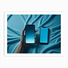 Two Smartphones Lie On A Blue Fabric With A Hand Holding One Art Print