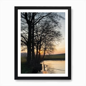 Tree silhouette and frozen pond at sunset Art Print