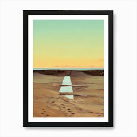 Beach Path at Sunset in Riviera. A digital illustration depicts a sandy beach at sunset, with a long, narrow wooden path leading towards the horizon. The sky is a gradient of soft blue, yellow, and orange, creating a peaceful and serene atmosphere. The path is made of light-colored wood planks, and it is surrounded by brown sand with footprints leading towards it. Art Print