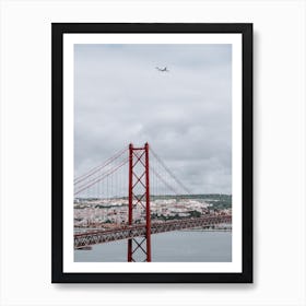 The 25 de Abril Bridge with an airplane flying over it. Art Print