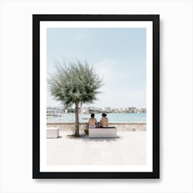 Two People Sitting On A Bench At The Coast Art Print