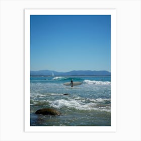 Surfer On The Beach With Surfboard Amongst Blue Skies, Rocks And Mountain Background In Byron Bay, Queensland Art Print