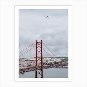 The 25 de Abril Bridge with an airplane flying over it. Art Print