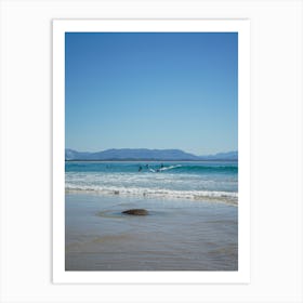 Surfers On The Beach In Popular, Byron Bay. Town And Mountains In The Background, In The Distance Over The Ocean Art Print