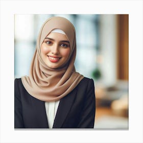 A young, beautiful, and confident Muslim woman wearing a hijab smiles at the camera. She is dressed in a business suit and is standing in an office setting. The background is blurred and out of focus. The woman's expression is one of happiness and contentment. She is proud of her accomplishments and is looking forward to the future. Canvas Print