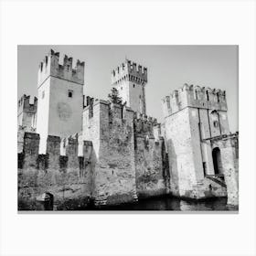 Medieval Castle by the Water Castello Scaligero Sirmione Lake Garda. A black and white illustration depicts a majestic medieval castle with towering stone walls and crenellated towers. The castle stands majestically by a body of water, possibly a moat or a lake, with a small bridge leading to the entrance. The intricate details of the stonework and the imposing presence of the castle create a sense of history and grandeur. Canvas Print