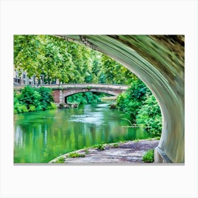 Tranquil Pathway Canal de Brienne Toulouse France. This image captures a tranquil riverside scene viewed from beneath a bridge. The lush greenery of the trees and bushes reflects beautifully on the calm, green-tinted water. In the background, another stone bridge spans the river, adding to the picturesque and serene atmosphere of the setting. Canvas Print