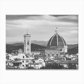 Florence Cathedral and Giotto's Campanile. This black and white photograph captures the iconic Florence Cathedral (Duomo) and Giotto's Campanile in Florence, Italy. The image showcases the architectural grandeur of the cathedral's large dome and the intricate details of the bell tower, set against a backdrop of rolling hills and a cloudy sky. The foreground includes a mix of traditional Italian buildings, adding to the historical ambiance of the scene. Canvas Print