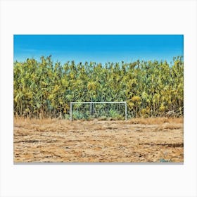 Overgrown Field with a Hidden Goalpost. A lush and overgrown field of tall green plants hides a forgotten goalpost, blending into the vibrant natural surroundings. The contrast between the dry, cracked earth and the dense vegetation highlights the untamed beauty of this rural scene under a clear blue sky. Canvas Print