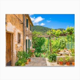 Mediterranean Spain. In the enchanting old village of Valldemossa on the idyllic Spanish island of Majorca, a picturesque scene awaits visitors. Traditional flower pots decorate the walls of the narrow streets and residential buildings, bringing color and beauty to the village's charming architecture. Canvas Print