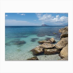 Clear, blue sea water and rocks on the beach Canvas Print