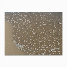 Foaming sea water and sand on the beach Canvas Print