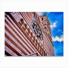 Rome: Striped Cathedral Facade with Rose Window. The image showcases the facade of a cathedral with distinctive horizontal red and white stripes. The architectural design features a series of arches supported by columns and a prominent rose window with intricate detailing. The sky in the background is a vibrant blue with scattered clouds, enhancing the visual appeal of the structure. Canvas Print