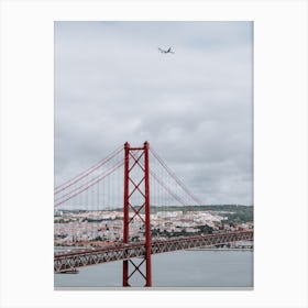 The 25 de Abril Bridge with an airplane flying over it. Canvas Print