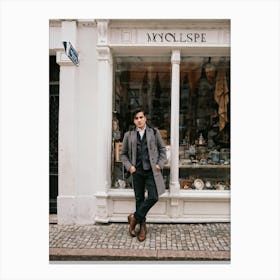 Youthful Spanish Man Adorned In Vintage Attire Standing In Front Of A Quaint Retro Shop Window Bo Canvas Print