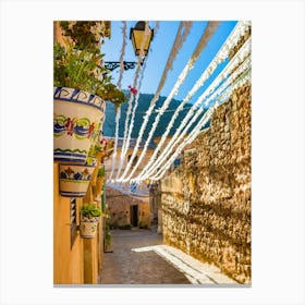 Spain, Valldemossa fiestas, lose yourself in the narrow, rustic streets of Valldemossa, a charming old village in Mallorca, Spain. Admire the Mediterranean stone buildings adorned with potted plants and flowers, showcasing the rich Balearic Island culture and history. Canvas Print